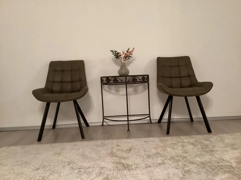 Zwei Sessel und ein kleiner Tisch mit Blumen in Ramonas Praxis
